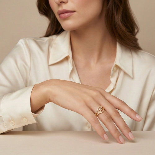 Elegancka modelka w stylu business premium prezentująca złoty pierścionek z falistym motywem i lśniącymi kamieniami.