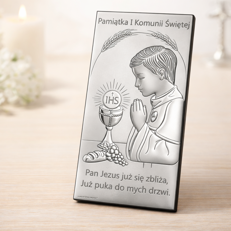 Srebrny obrazek komunijny dla chłopca na jasnej komodzie – ujęcie pod kątem 30–45 stopni