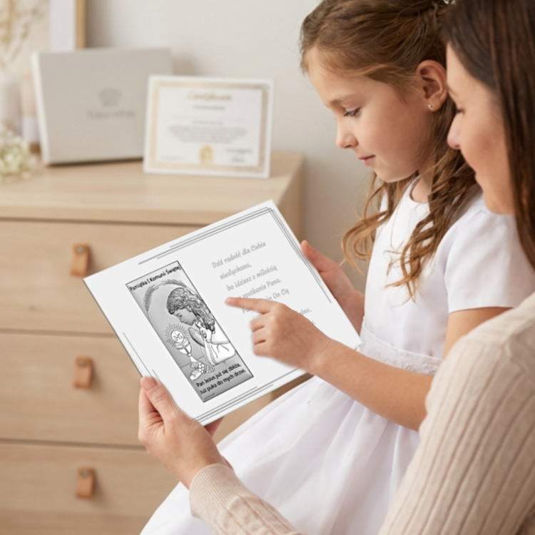 Pamiątka na I Komunię dla dziewczynki – dziecko z mamą ogląda srebrny obrazek komunijny i czyta życzenia na kartce, ujęcie lifestyle