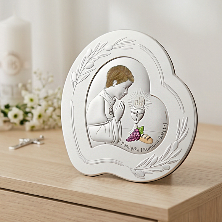 Pamiątka I Komunii Świętej dla chłopca – srebrny obrazek 925 serce z motywem IHS w aranżacji na komodzie, świeca w tle