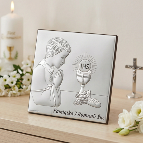 Pamiątka I Komunii Świętej – srebrny kwadratowy obrazek komunijny dla chłopca z motywem IHS, aranżacja na komodzie, świeca i krzyż w tle