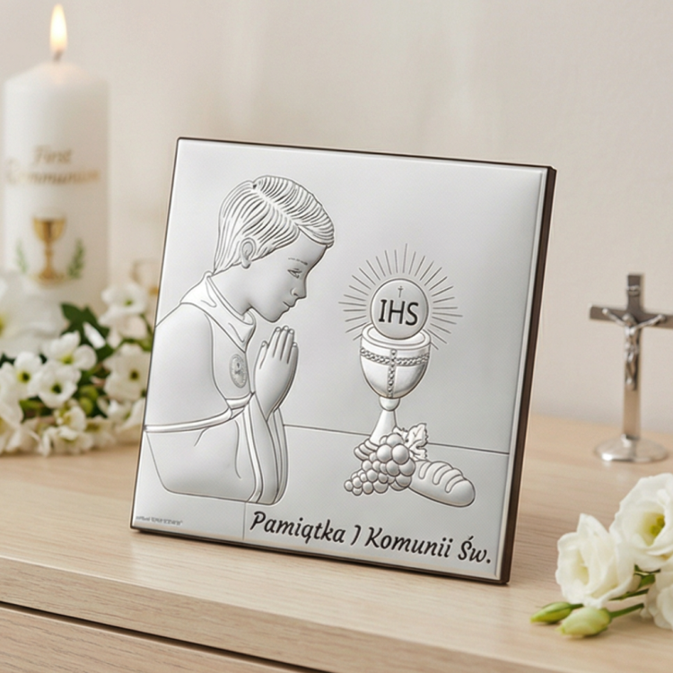 Pamiątka I Komunii Świętej – srebrny kwadratowy obrazek komunijny dla chłopca z motywem IHS, aranżacja na komodzie, świeca i krzyż w tle