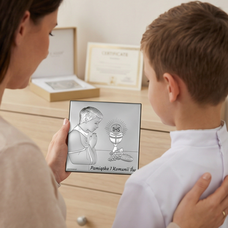 Prezent na I Komunię dla chłopca – dziecko z mamą ogląda srebrny kwadratowy obrazek z motywem IHS i kielicha, ujęcie lifestyle