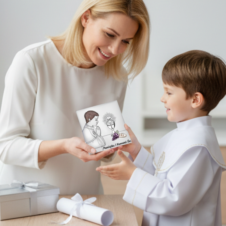 Prezent na I Komunię dla chłopca – mama wręcza srebrny kwadratowy obrazek z motywem IHS i winogronami, ujęcie lifestyle