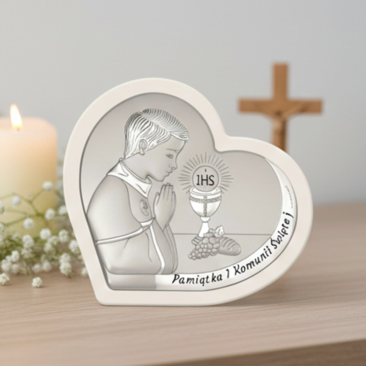 Pamiątka I Komunii Świętej – srebrny obrazek serce dla chłopca z motywem IHS, aranżacja na komodzie ze świecą i krzyżem w tle