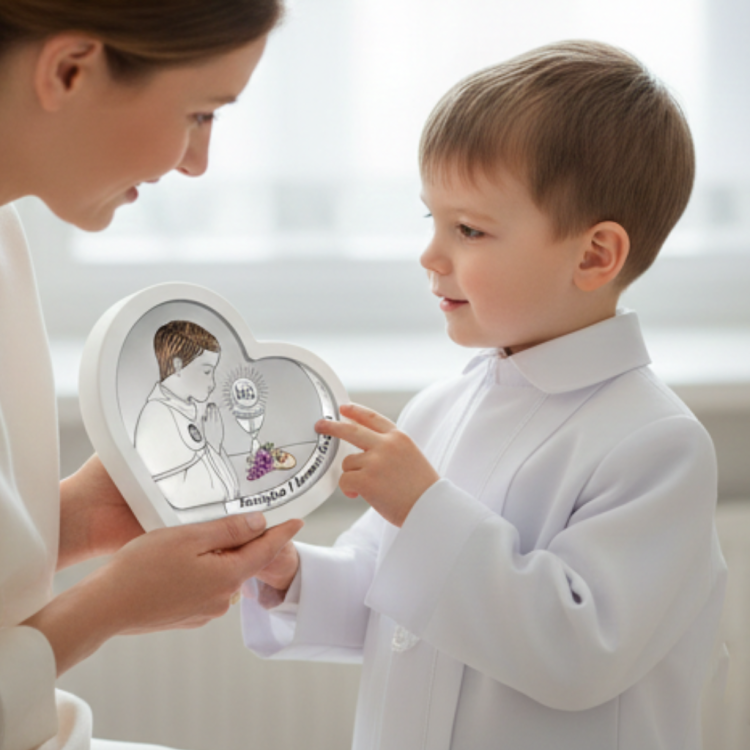 Prezent na I Komunię dla chłopca – dziecko wskazuje detal na srebrnym obrazku w kształcie serca z hostią IHS i winogronami, ujęcie lifestyle