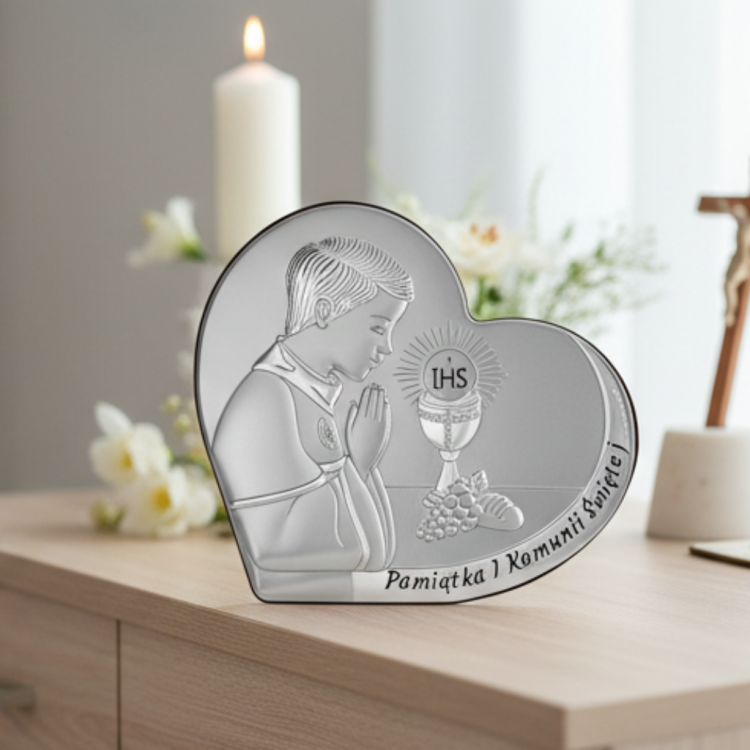 Pamiątka I Komunii Świętej dla chłopca – srebrny obrazek serce z motywem IHS, aranżacja na komodzie ze świecą i krzyżem w tle