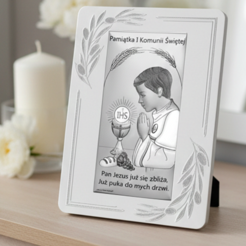 Pamiątka Pierwszej Komunii Świętej – obrazek z chłopcem w modlitwie i hostią IHS ustawiony na komodzie przy świecy