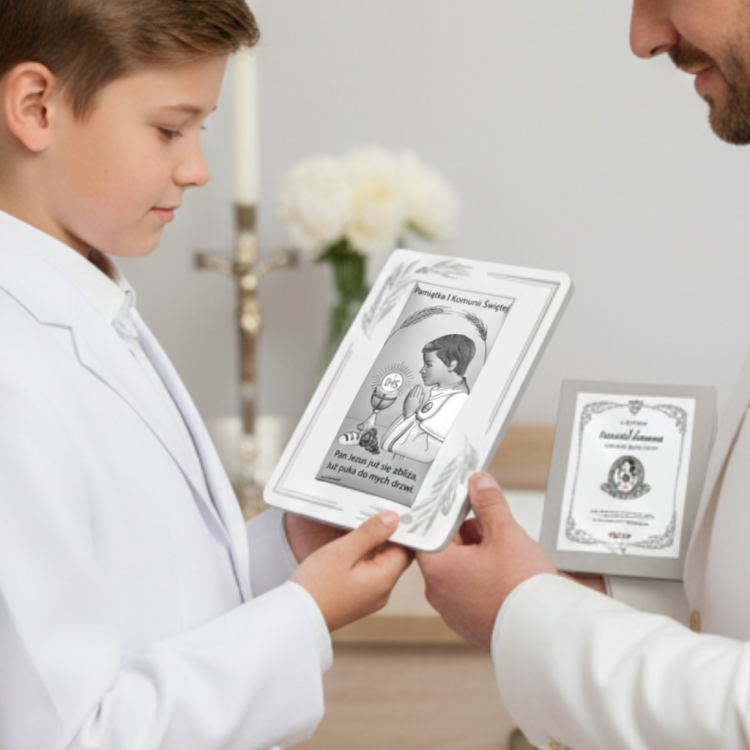 Pamiątka Pierwszej Komunii Świętej – chłopiec w białym garniturze otrzymuje srebrny obrazek z hostią IHS