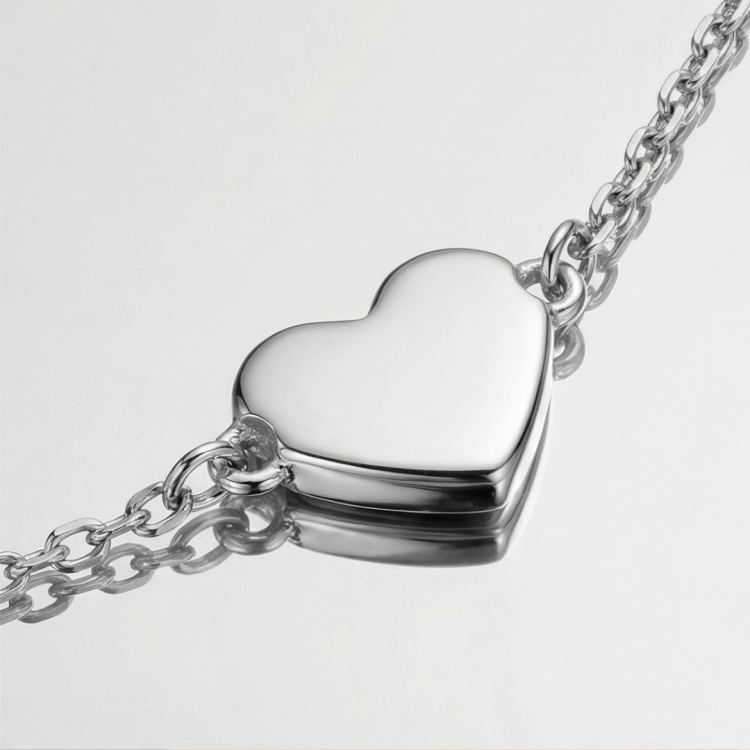 Zbliżenie na gładką srebrną zawieszkę w kształcie serca przy łańcuszku