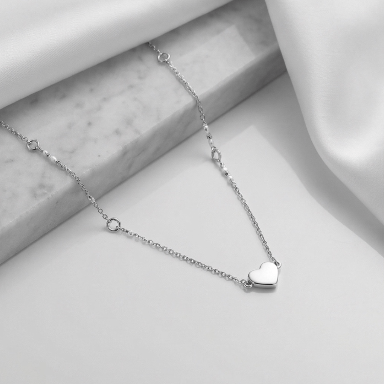 Srebrny naszyjnik z sercem na eleganckim tle z marmurem i tkaniną