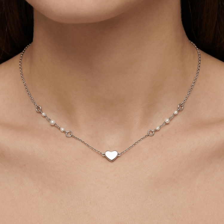 Srebrny naszyjnik z małą zawieszką serce na szyi – ujęcie na modelce