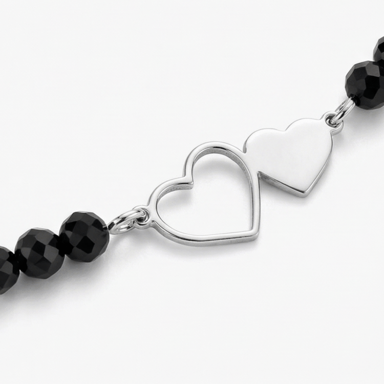 zbliżenie srebrnej zawieszki dwa serca z czarnymi koralikami
