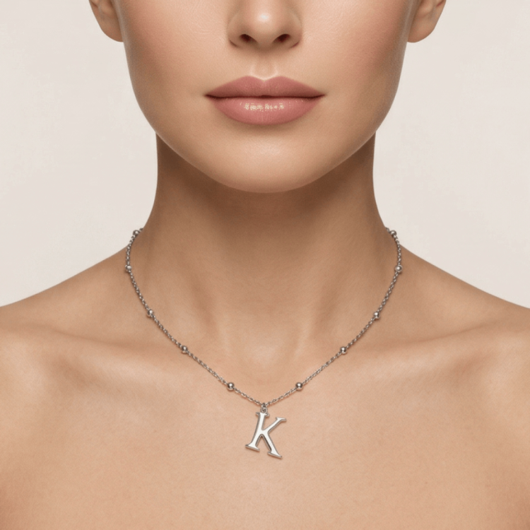 srebrny naszyjnik z literą K na szyi modelki