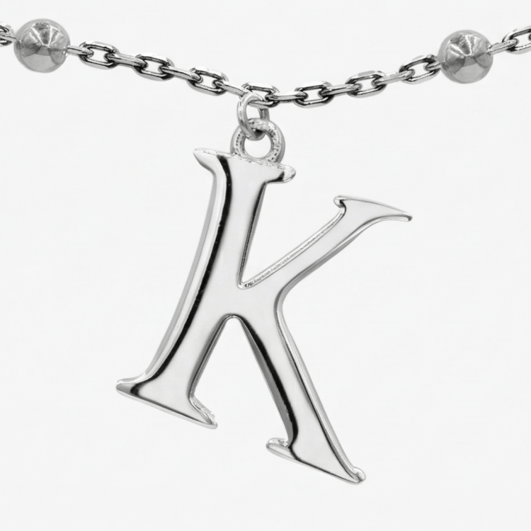 zbliżenie srebrnej zawieszki w kształcie litery K