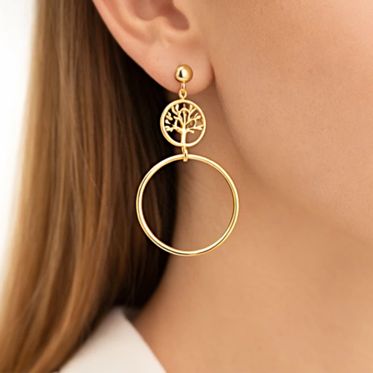Kolczyk wiszący w złotym kolorze z motywem drzewa życia i dużym okręgiem na uchu – zbliżenie