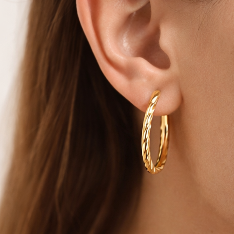 Złoty kolczyk koło o skręcanej fakturze na uchu