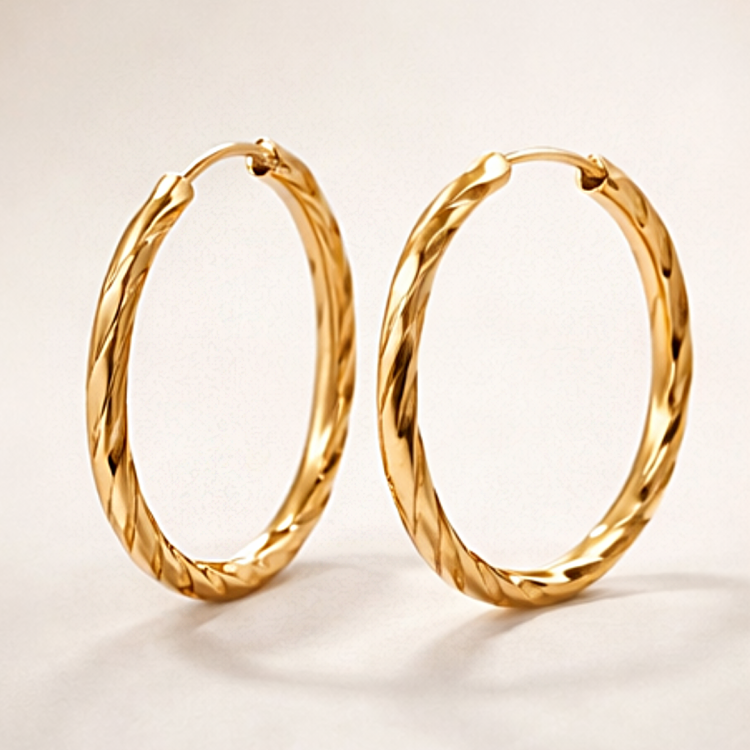 Owalne złote kolczyki koła o skręcanej fakturze na jasnym tle