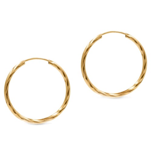 Złote kolczyki koła o skręcanej fakturze na jasnym tle