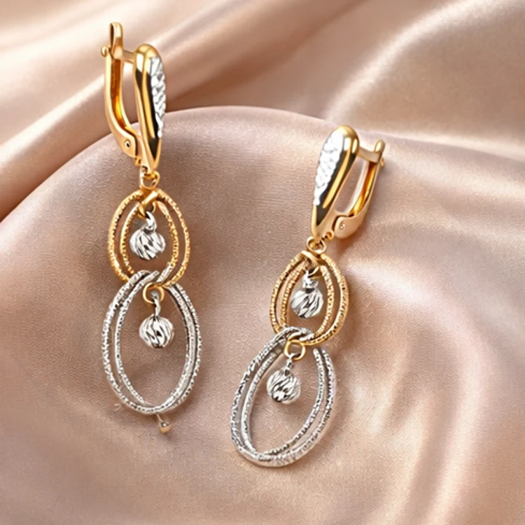 Dwukolorowe kolczyki wiszące z owalnymi zawieszkami na satynowej tkaninie