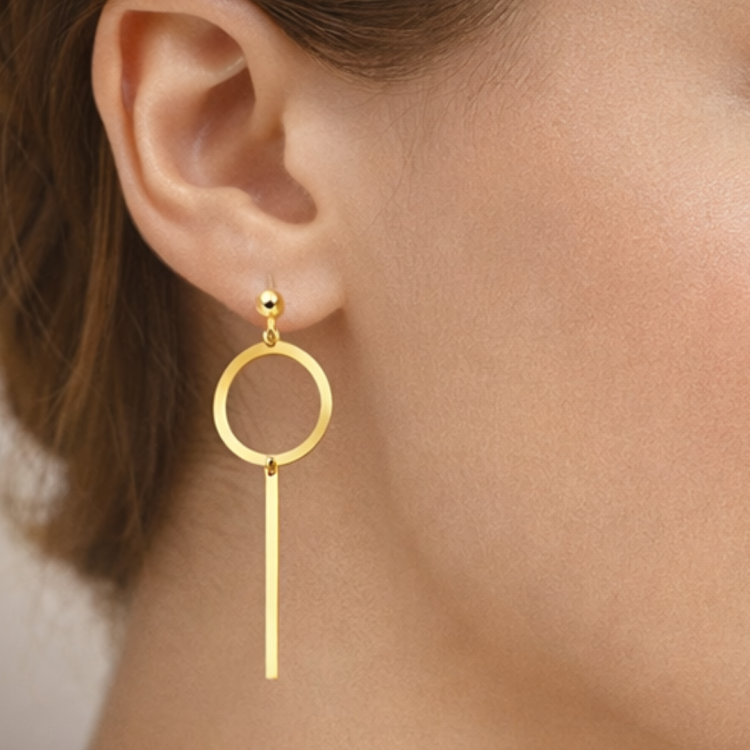 Złoty kolczyk wiszący z okrągłym elementem i pionową pałeczką na uchu