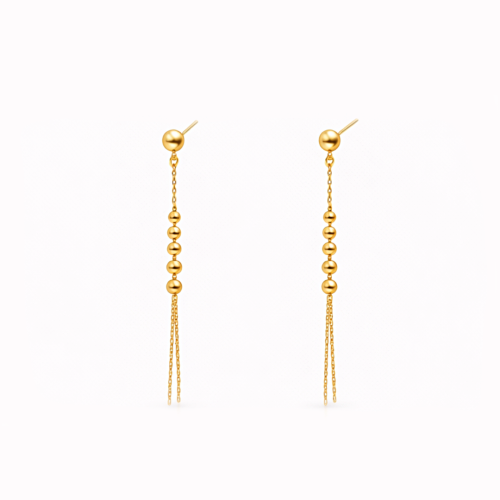 Złote kolczyki wiszące z kuleczkami i podwójnym łańcuszkiem na jasnym tle