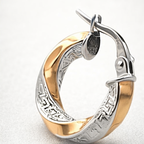 Zbliżenie na dwukolorowy kolczyk koło o skręcanej formie z ozdobnym grawerowanym wzorem i zapięciem