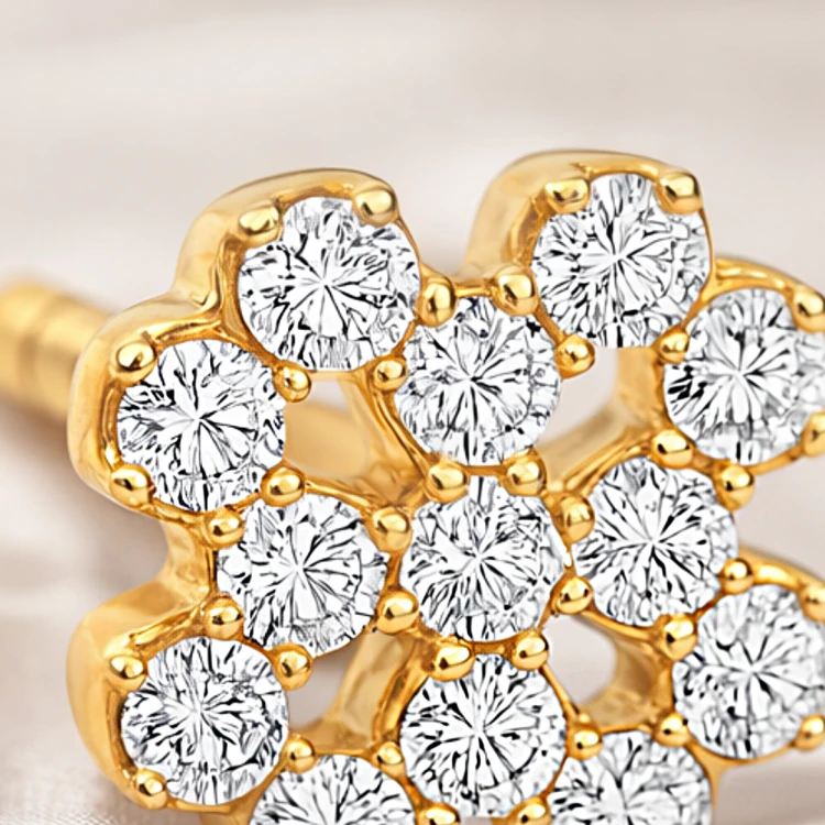 Zbliżenie na złoty kolczyk sztyft z kwiatowym układem białych kamieni i połyskującym wykończeniem