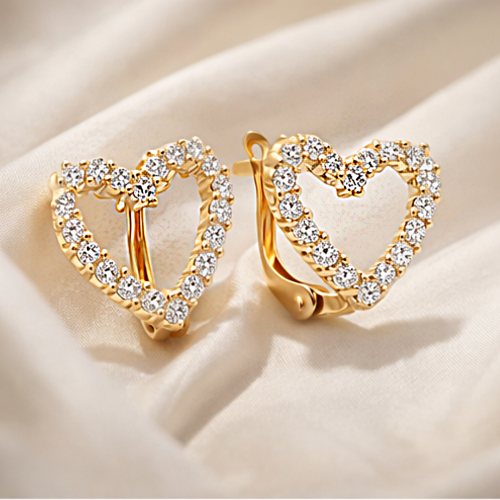 Złote kolczyki serca z cyrkoniami ułożone na jasnej tkaninie