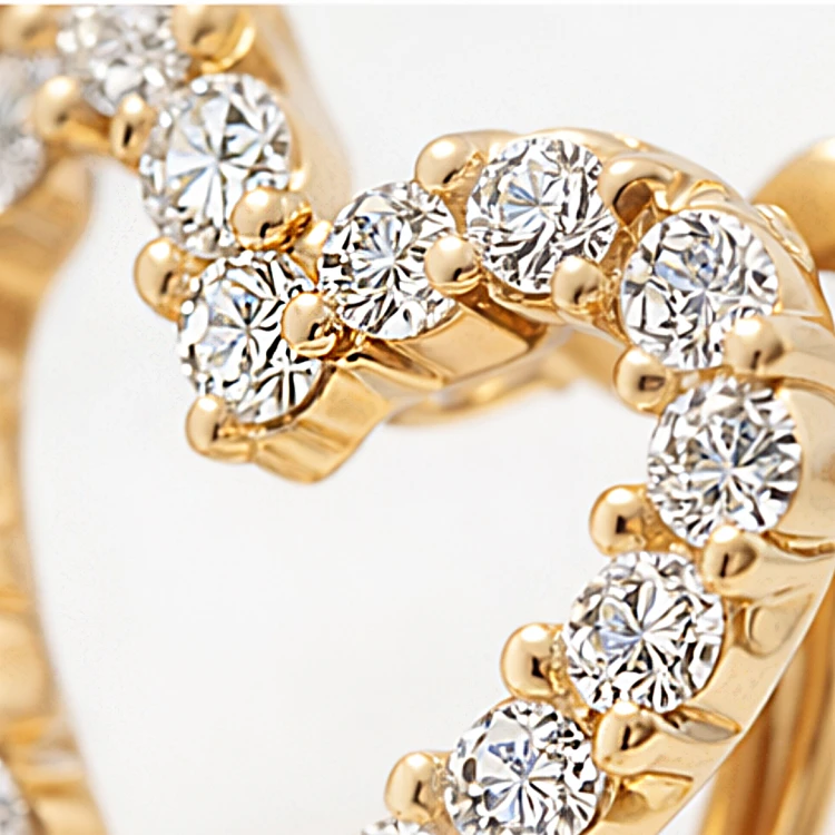 Złoty kolczyk w kształcie serca ozdobiony cyrkoniami w zbliżeniu