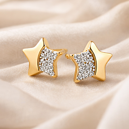 Złote kolczyki sztyfty gwiazdki z cyrkoniami ułożone na jasnej tkaninie