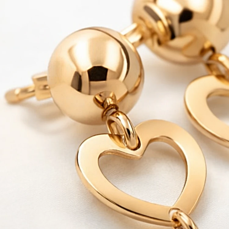 Złoty kolczyk wiszący z ażurowym sercem w zbliżeniu