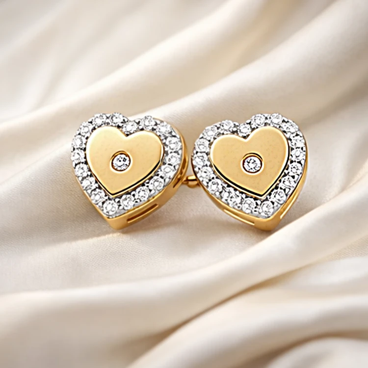 Złote kolczyki sztyfty serca z cyrkoniami ułożone na jasnej tkaninie