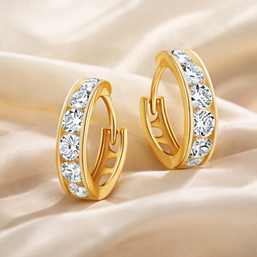 Złote kolczyki koła z białymi cyrkoniami na satynowej tkaninie