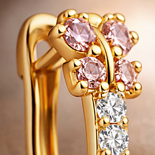 Zbliżenie złotego kolczyka z różowymi kamieniami i białymi cyrkoniami