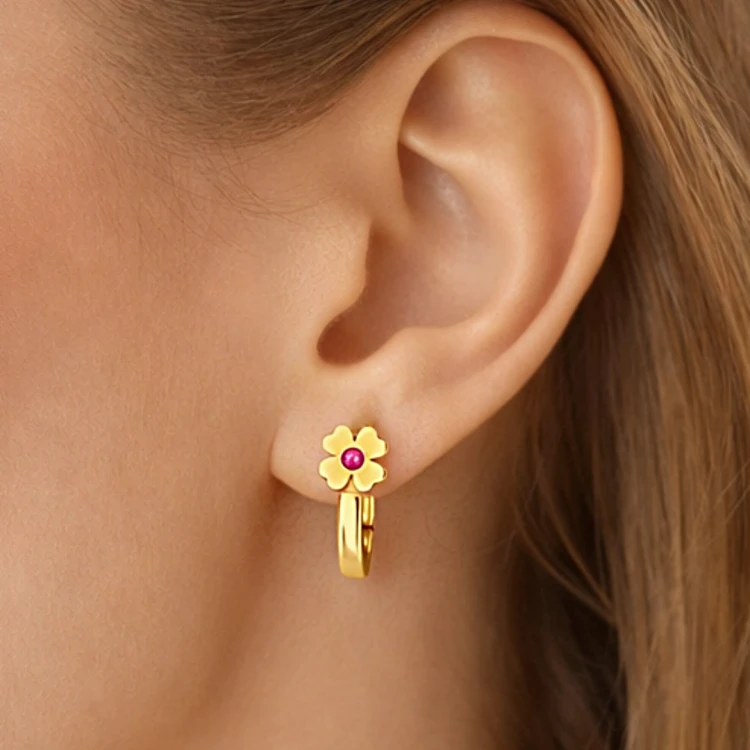 Złoty kolczyk z kwiatkiem i różowym kamieniem na uchu