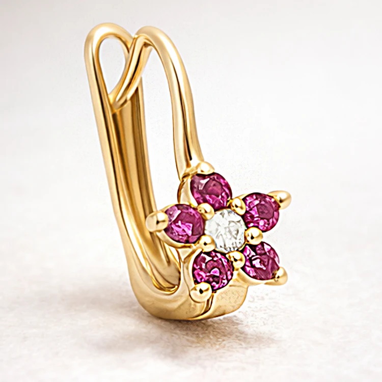 Złoty kolczyk z kwiatowym motywem z różowych kamieni w zbliżeniu