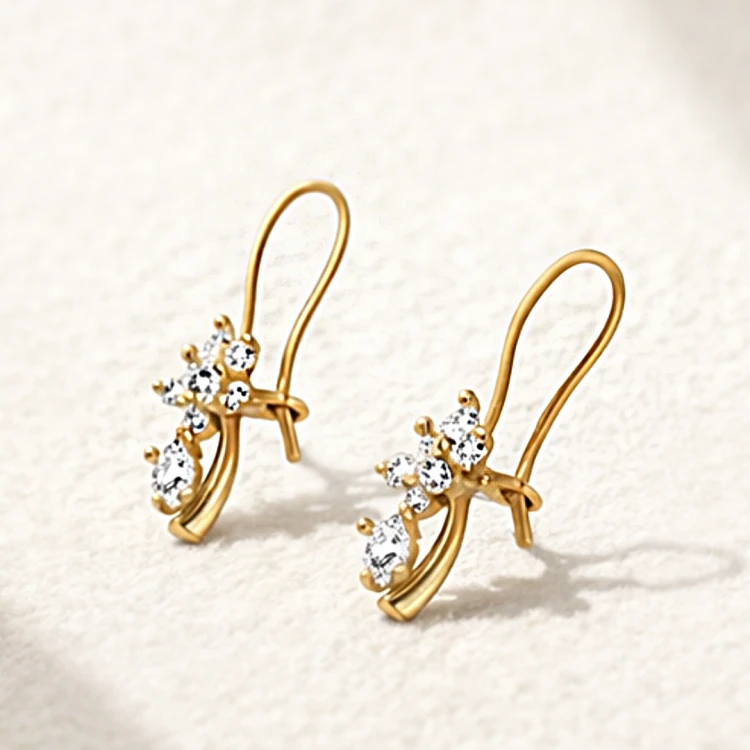 Złote kolczyki z białymi kamieniami na jasnym tle