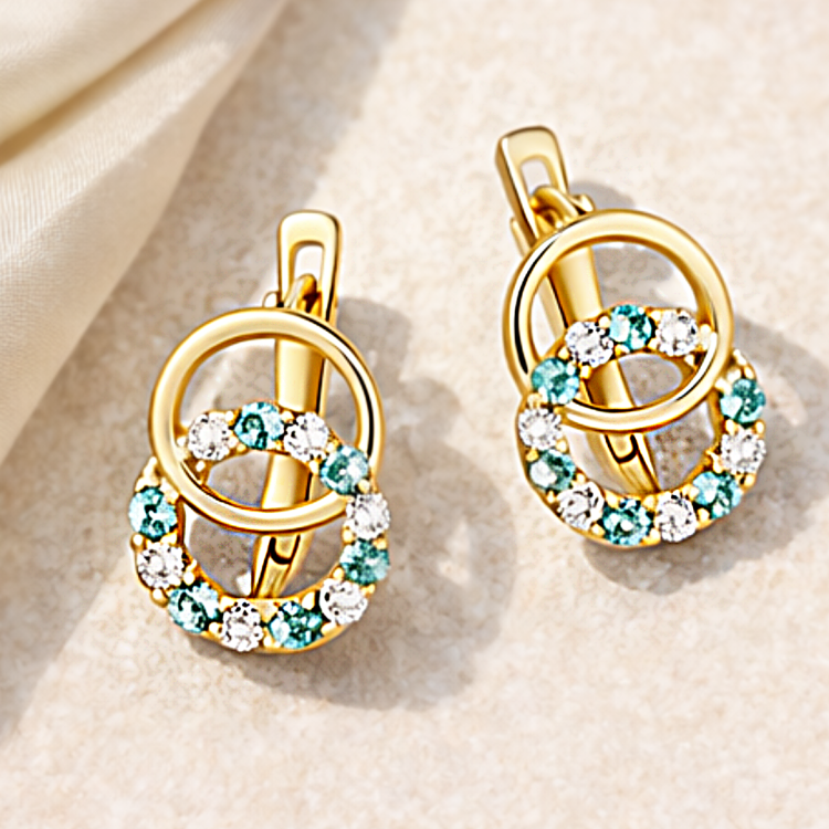 Para złotych kolczyków z okrągłą zawieszką i niebieskimi, białymi kamieniami – ujęcie pod kątem