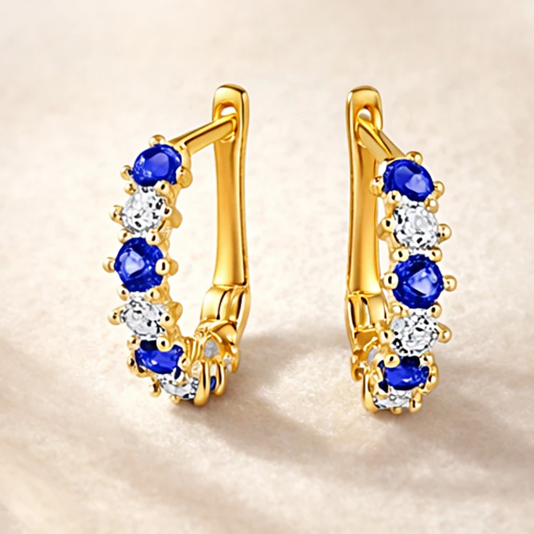 Para złotych kolczyków z niebieskimi i białymi kamieniami – ujęcie pod kątem