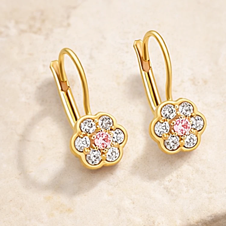 Para złotych kolczyków z kwiatowym zdobieniem i białymi kamieniami – ujęcie pod kątem