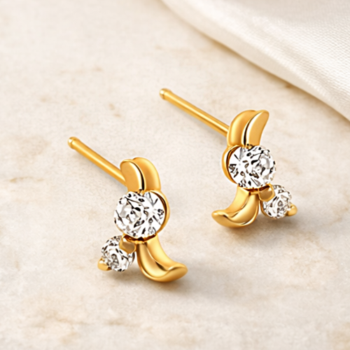 Para złotych kolczyków z białymi kamieniami i subtelnym falistym zdobieniem – ujęcie pod kątem