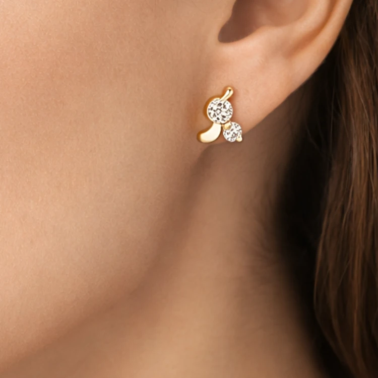 Złoty kolczyk sztyft z białymi kamieniami i falistym motywem na uchu