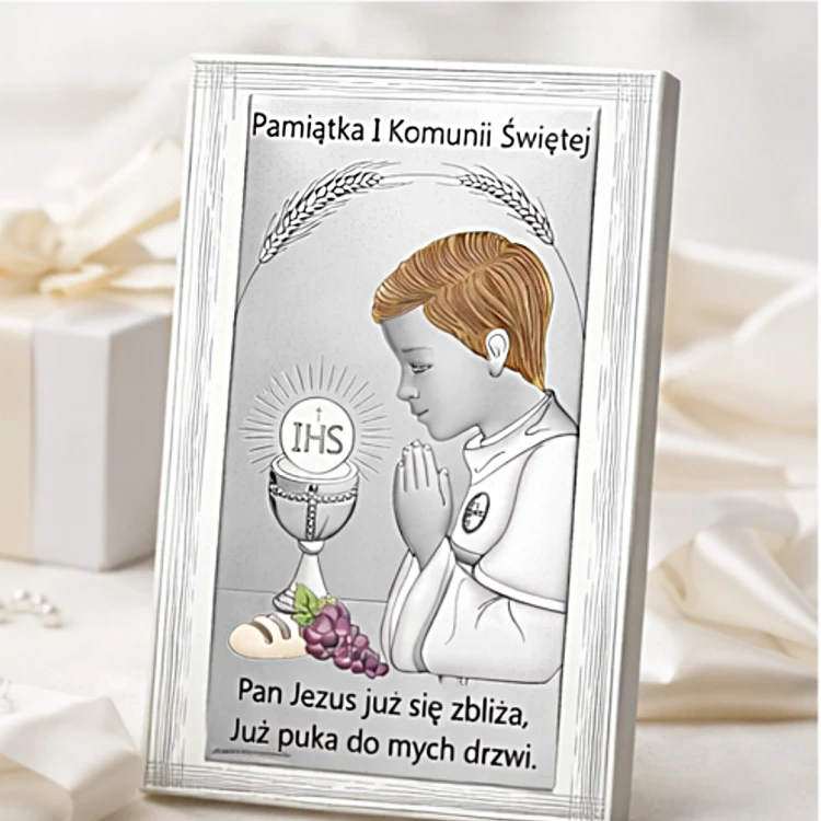 Obrazek komunijny dla chłopca w srebrnej ramce ustawiony na jasnym tle prezentowym