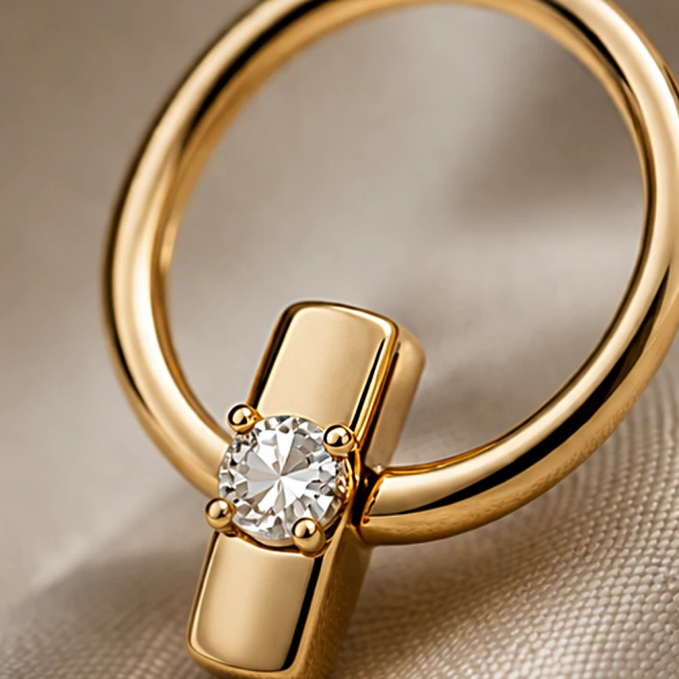 Złoty kolczyk sztyft w kształcie okręgu z ozdobną cyrkonią – zbliżenie