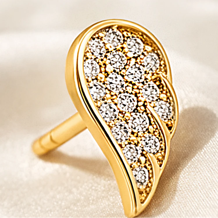 Złoty kolczyk sztyft w kształcie skrzydła wysadzany cyrkoniami – zbliżenie