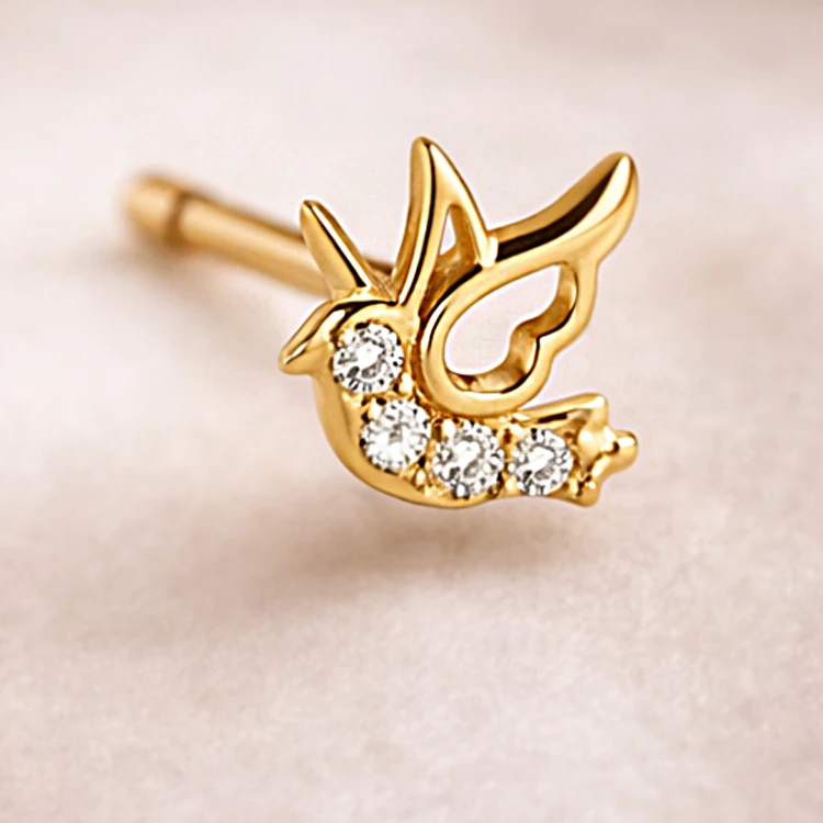 Zbliżenie złotego kolczyka jaskółki zdobionego białymi cyrkoniami