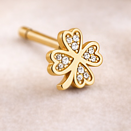 Zbliżenie złotego kolczyka koniczyny zdobionego białymi cyrkoniami