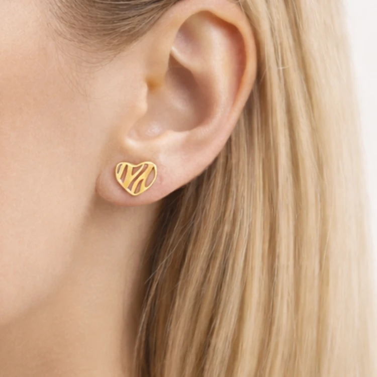 Złoty kolczyk serce ażurowe we wzór fal na uchu